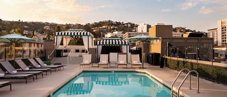 Una piscina al aire libre, camas de piscina con cargo, sombrillas