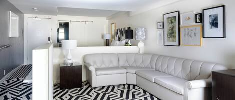 A modern living room with a white leather sofa, a patterned rug, and a wall with framed artwork.