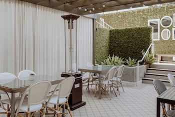 A modern restaurant with a long counter, cushioned seating, and pendant lighting. at Chamberlain West Hollywood
