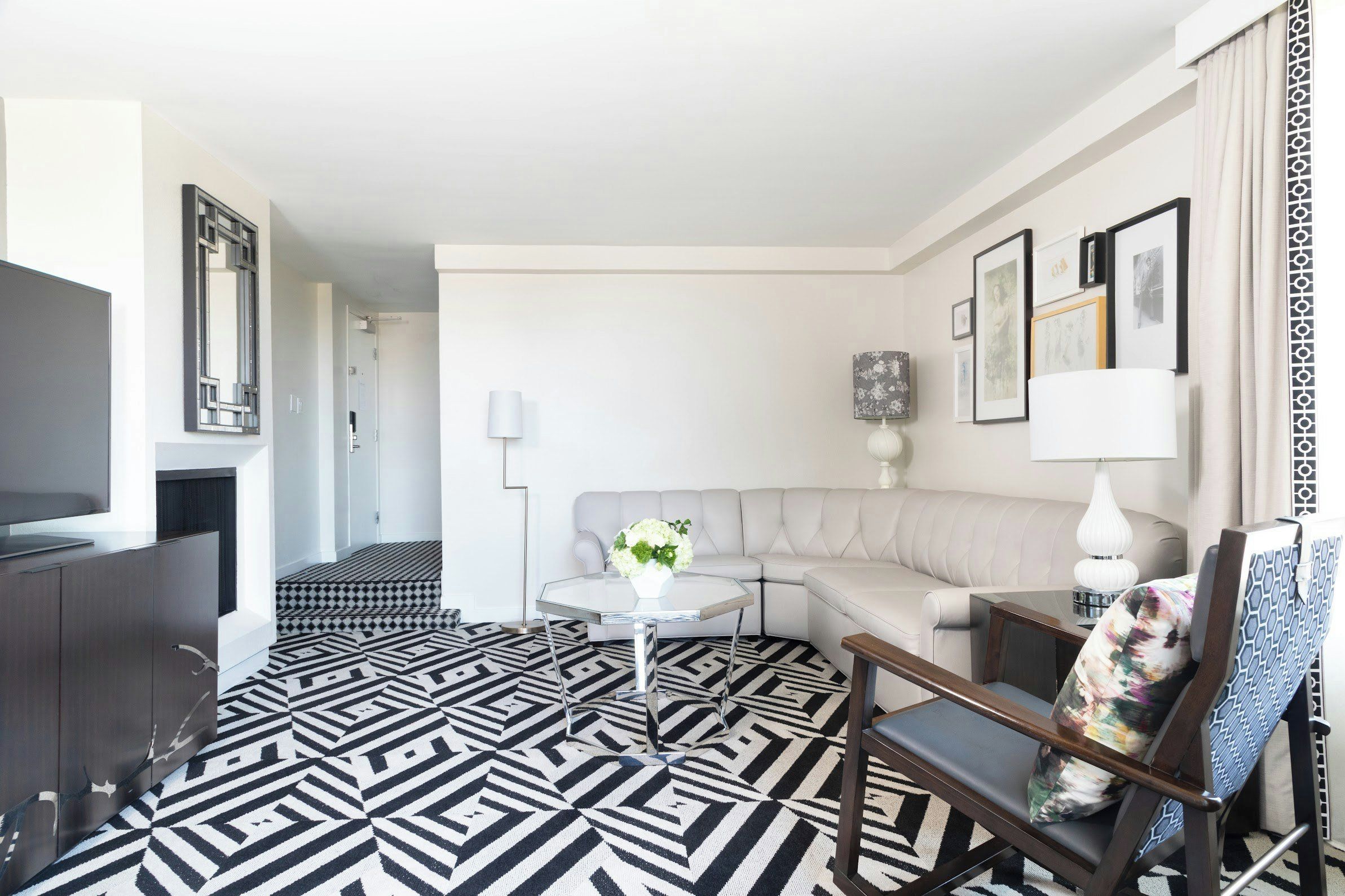 A modern living room with a sofa, a coffee table, a TV, and a patterned floor.