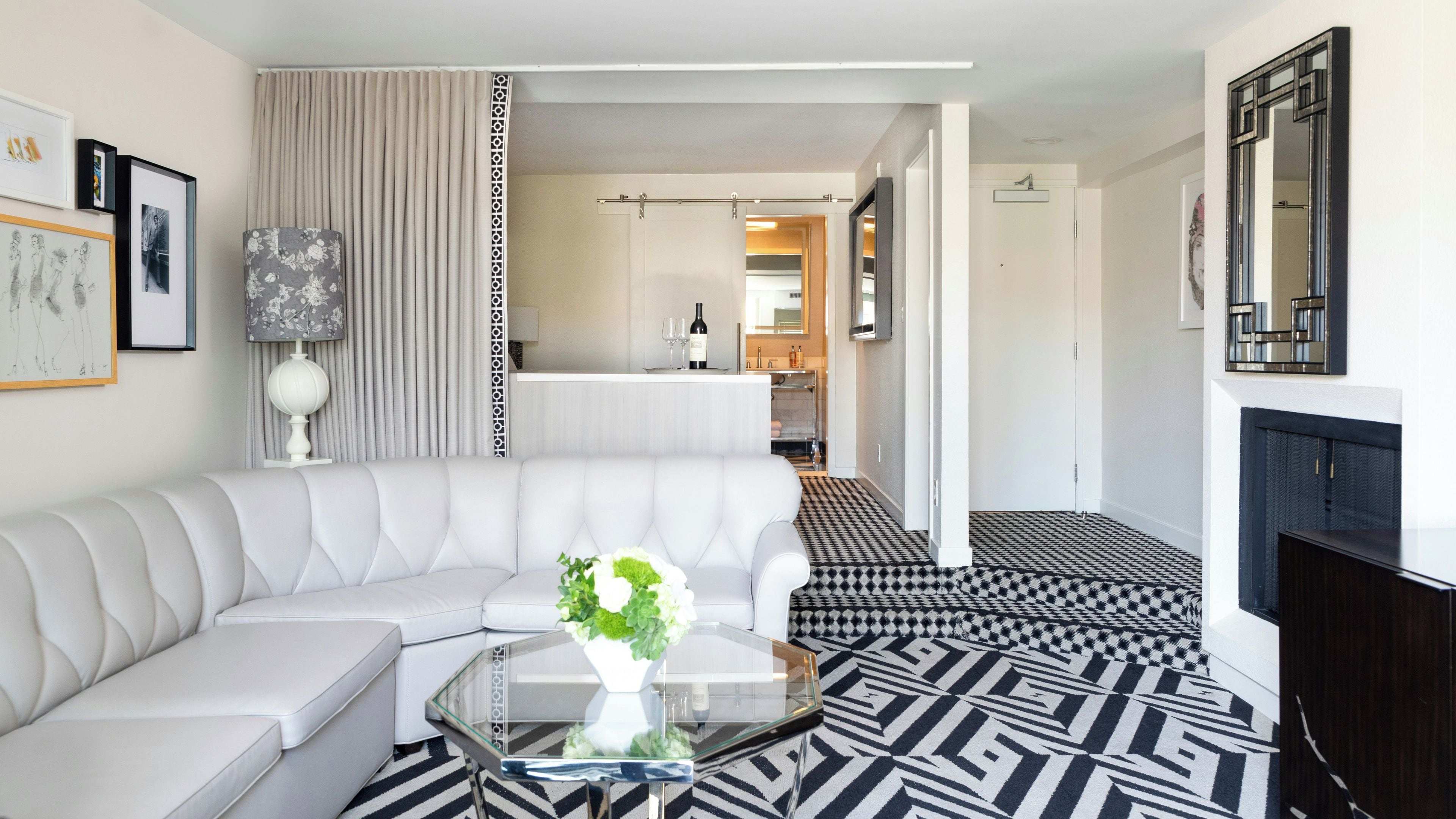 A modern living room with a white sofa, a glass coffee table, and a patterned floor.