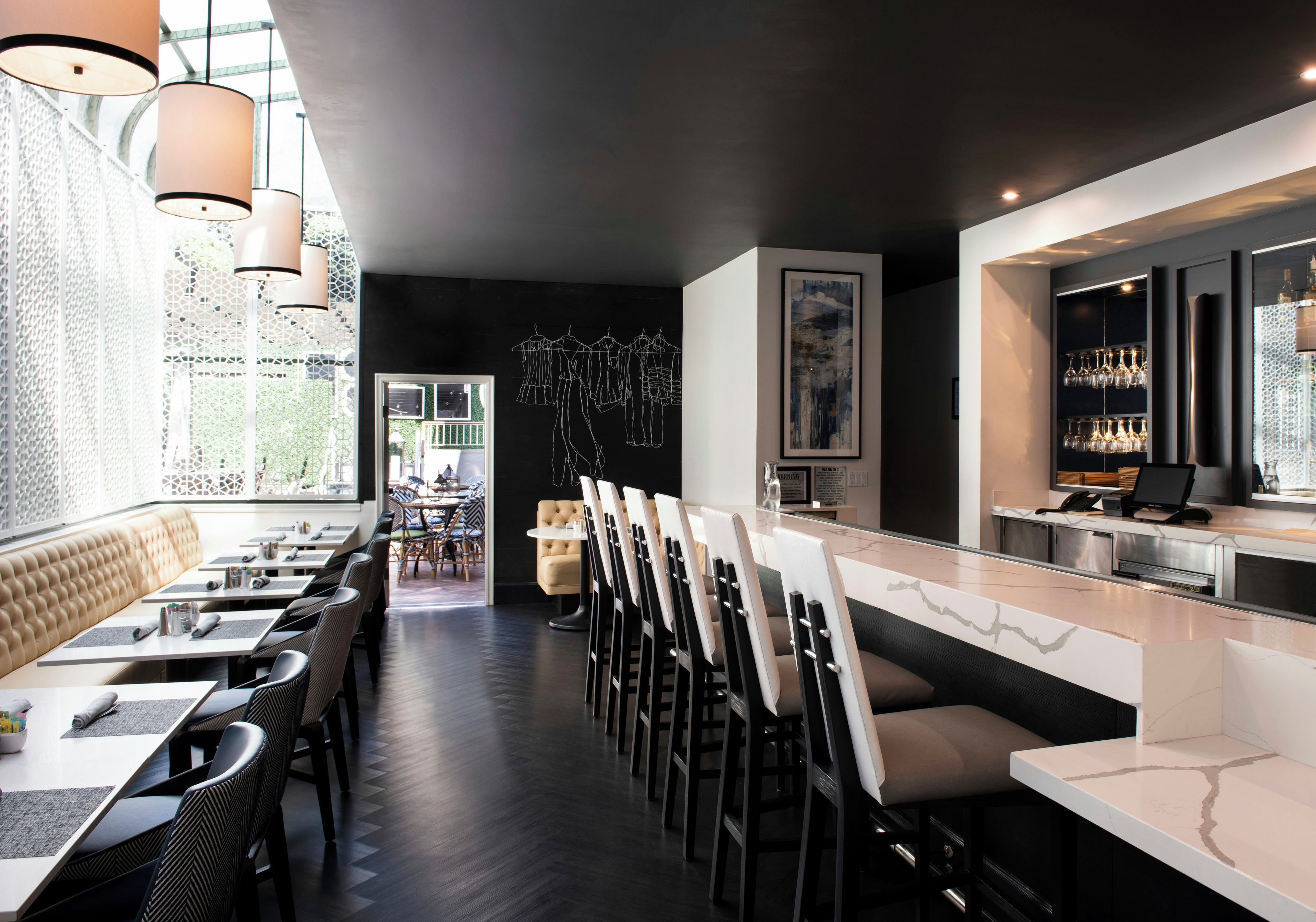 A modern restaurant interior with a bar area, dining tables, and chairs.