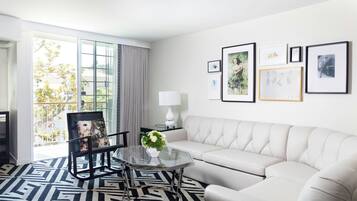Ein modernes Wohnzimmer mit einem Glastisch, einem weißen Sofa und einem großen Fenster mit Vorhängen.