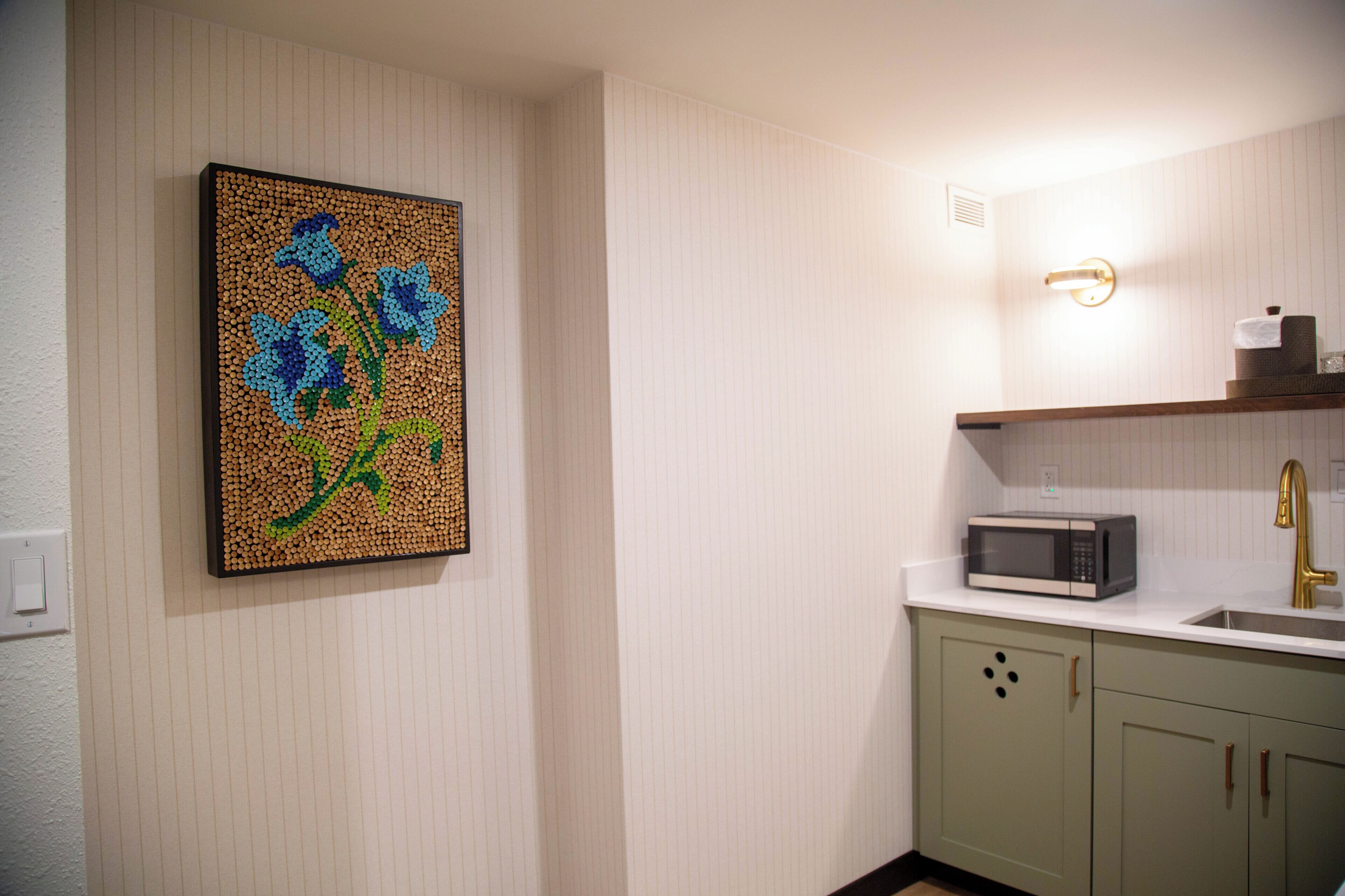 A kitchen with a microwave, sink, and green cabinets.