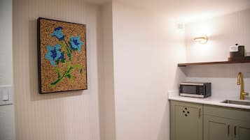 A kitchen with a microwave, sink, and green cabinets.