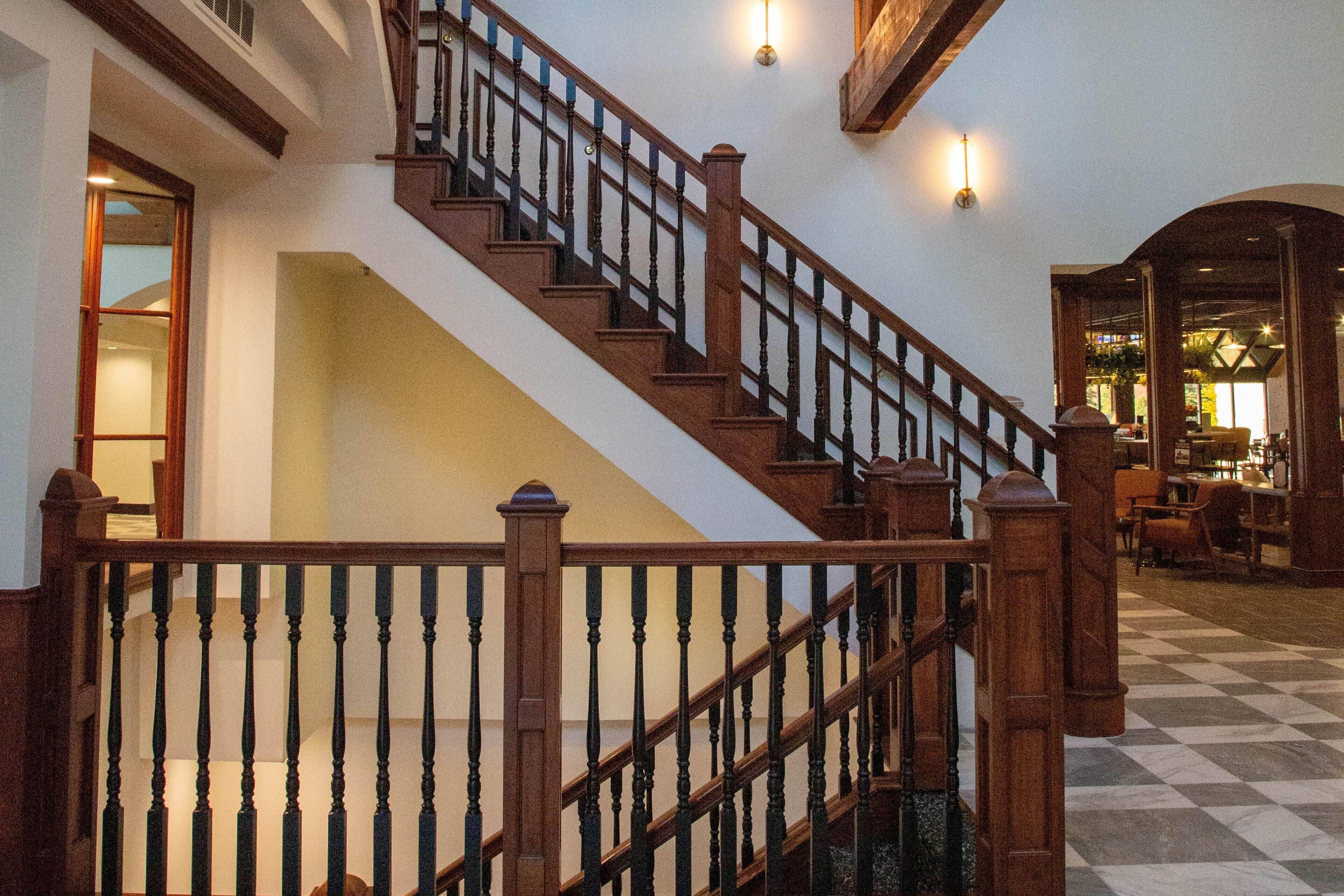 A grand staircase with wooden balusters and a checkered floor.