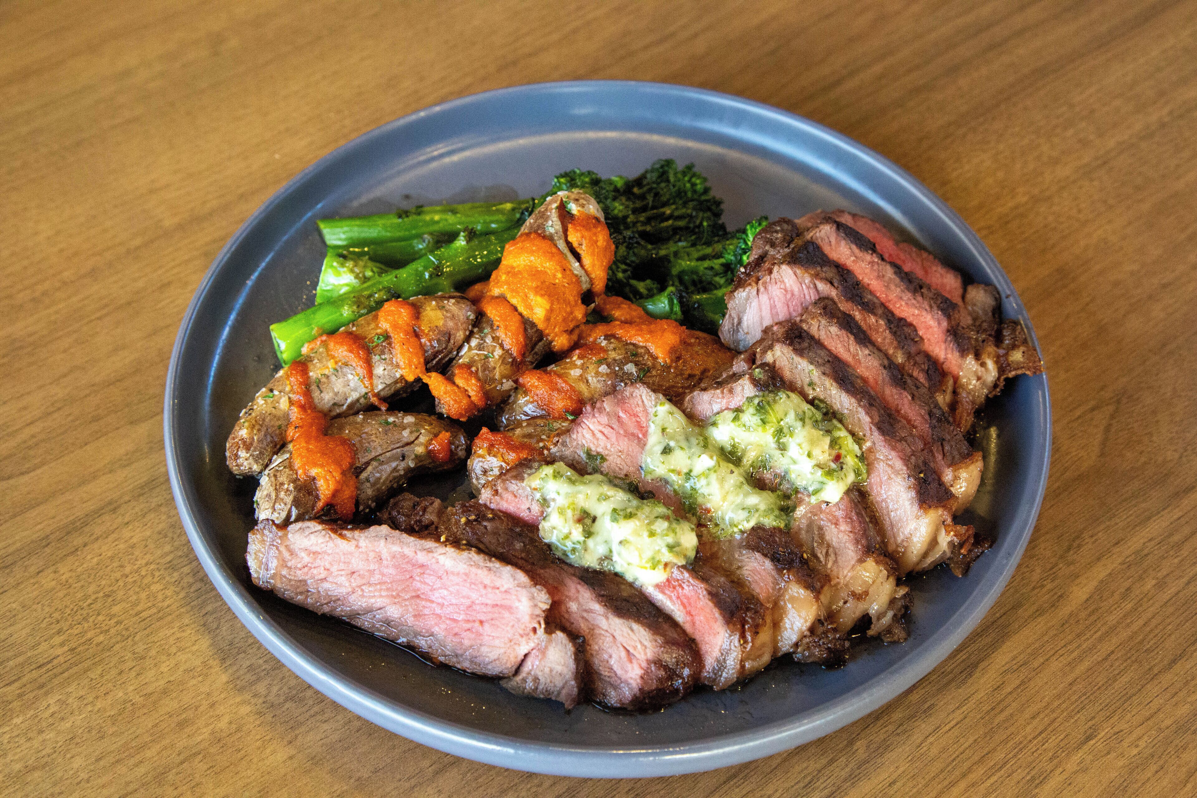 A plate of food with steak, broccoli, and carrots.