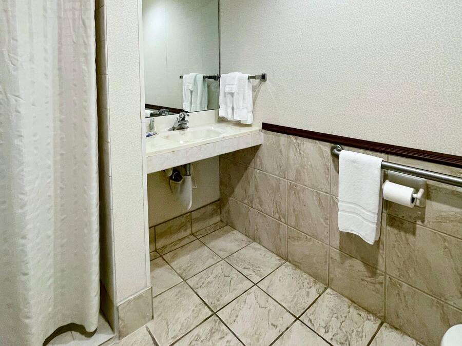 A bathroom with a sink, mirror, and two towels hanging on the wall.