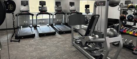 A gym with treadmills, weight machines, and free weights.