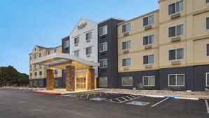 A multi-story hotel with a modern facade, a prominent entrance, and a parking lot with handicapped spaces.