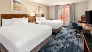 A hotel room with two beds, a desk, a chair, a TV, and artwork on the walls.
