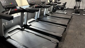 A gym with multiple treadmills, each equipped with a digital display and control panel.