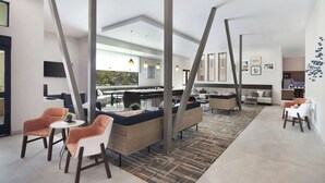 Een modern interieur met een centrale zithoek, een keuken op de achtergrond en een eethoek met een lange tafel.