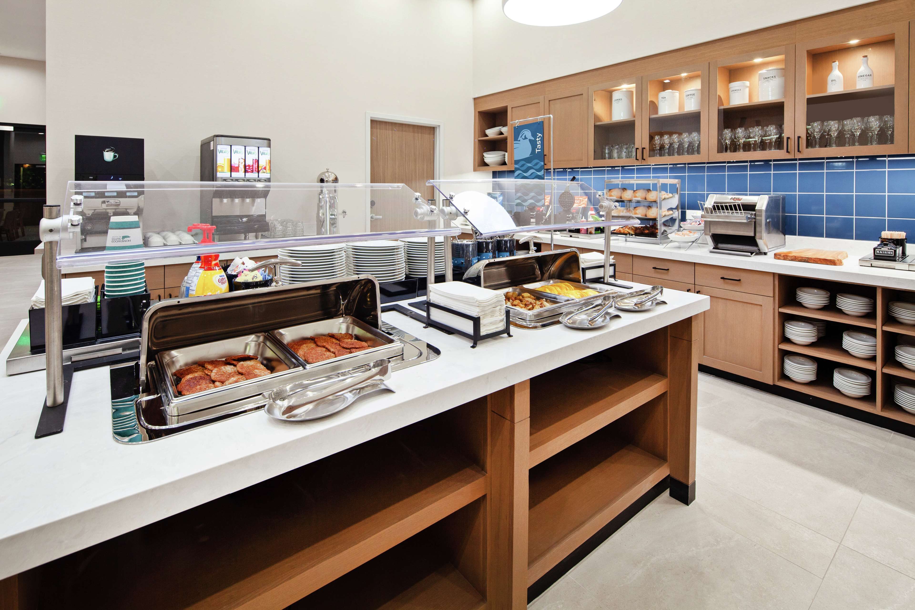Disposição de buffet com diversos pontos de comida, uma máquina de café e um dispensador de bebidas.