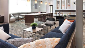 Een moderne hotellobby met een zithoek, een bar en een groot raam.