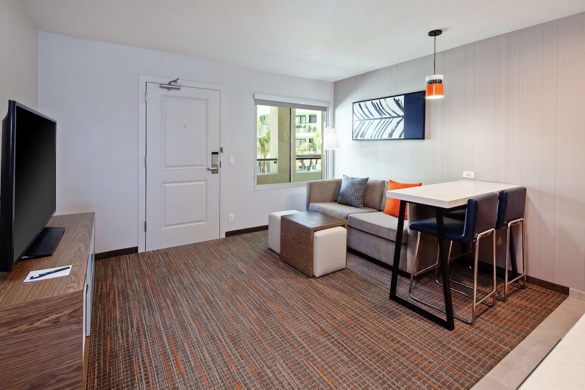 Une chambre d’hôtel moderne avec un canapé, une petite table et un téléviseur.