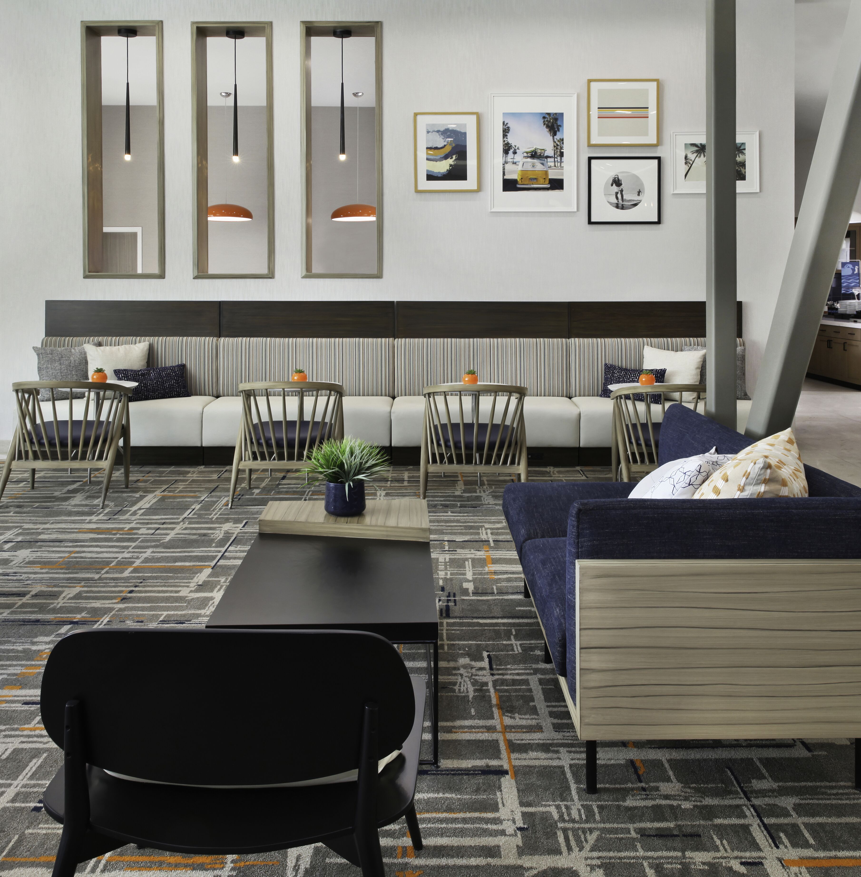 A modern lounge area with a sofa, chairs, a small table, and artwork on the wall.