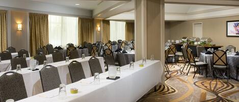 A conference room with multiple tables, chairs, and a buffet area.