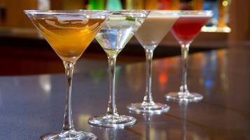 Tres copas de martini con bebidas de colores distintos sobre una barra.
