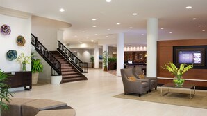 A spacious lobby with a staircase, seating area, and a reception desk.