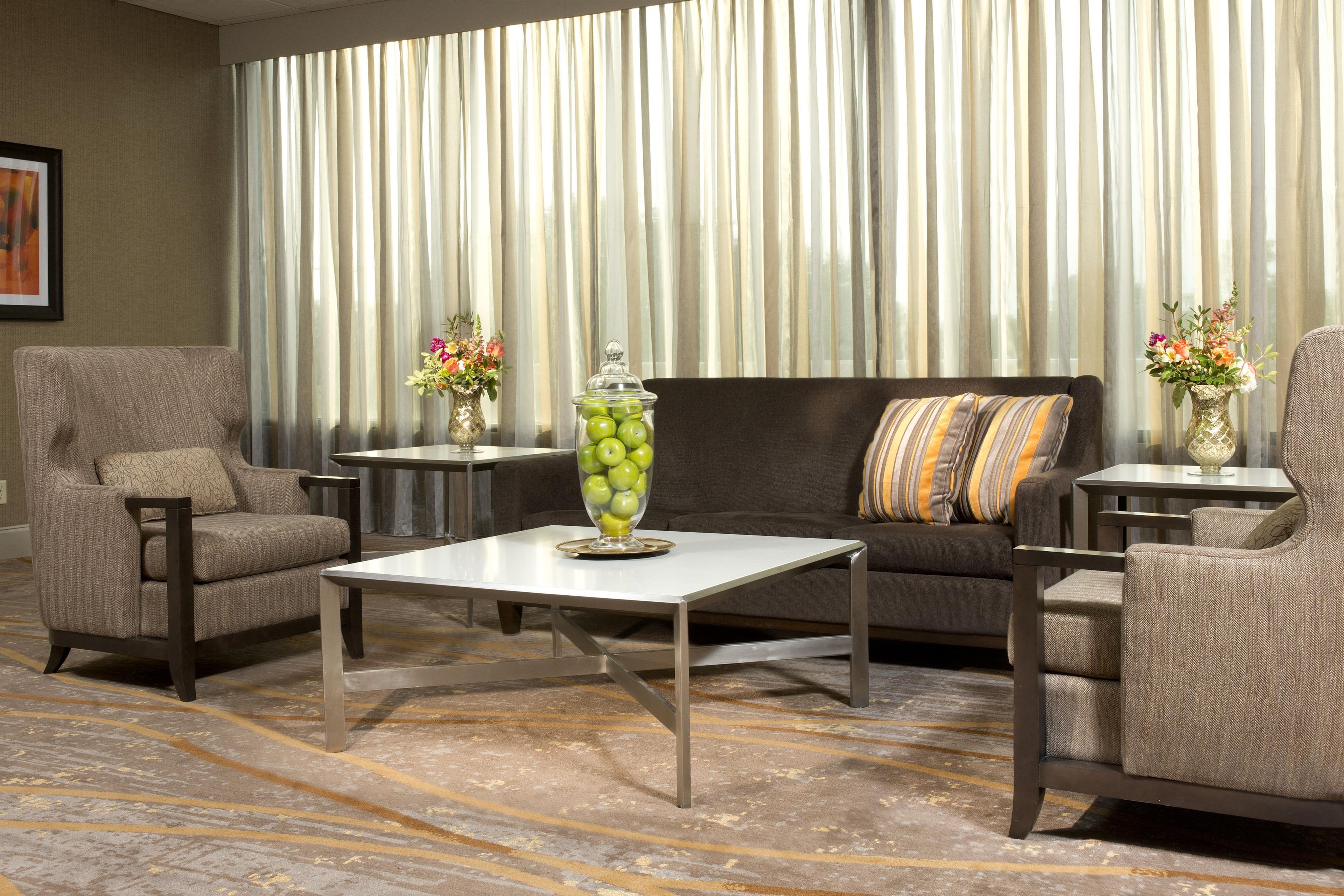 A modern living room with a sofa, armchairs, a coffee table, and two side tables with vases.