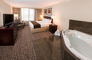 A hotel room with a bed, a TV, a desk, a chair, a lamp, a nightstand, and a bathtub. - DoubleTree by Hilton Hotel Lafayette (Lafayette)