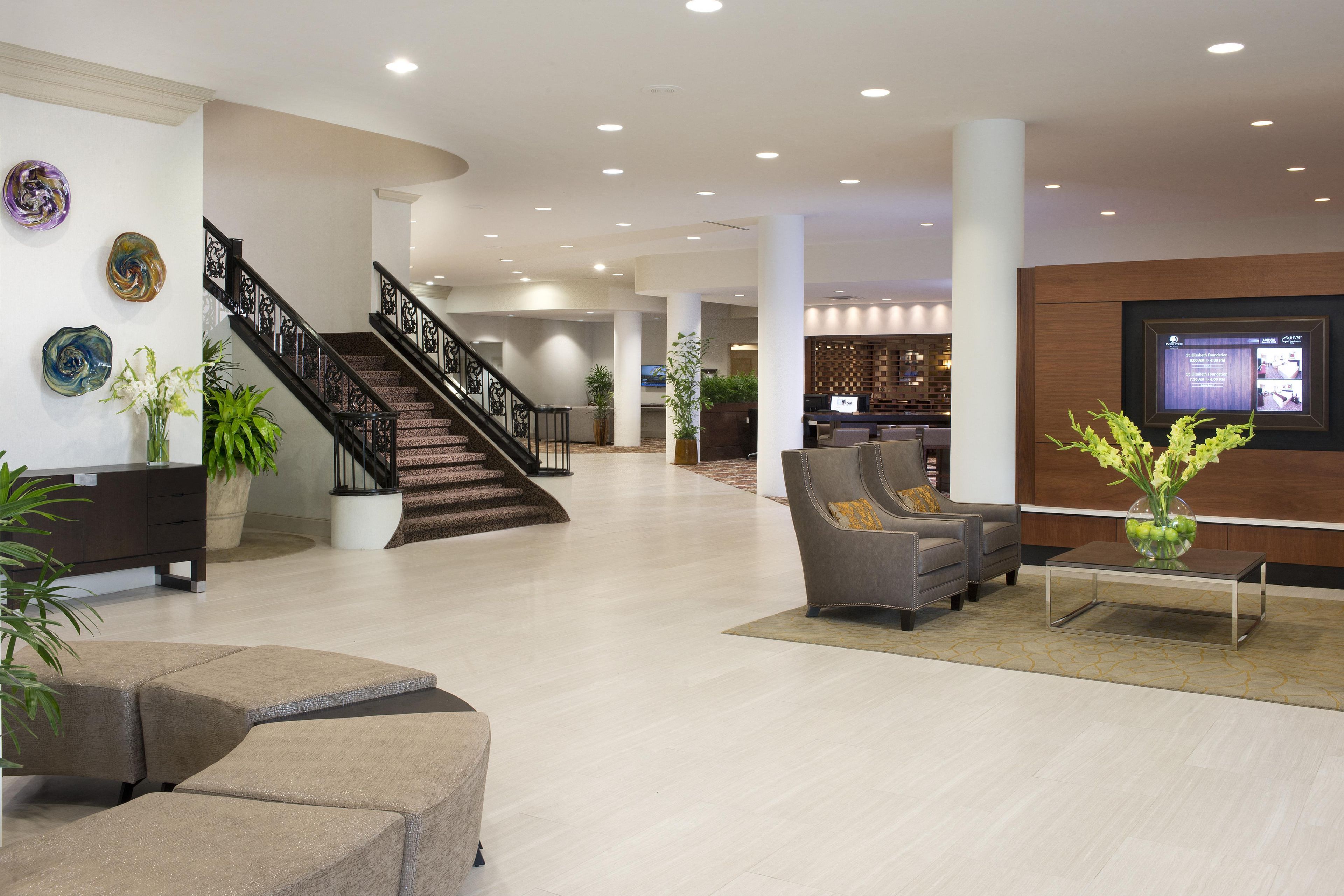 A spacious lobby with a staircase, seating area, and a reception desk.