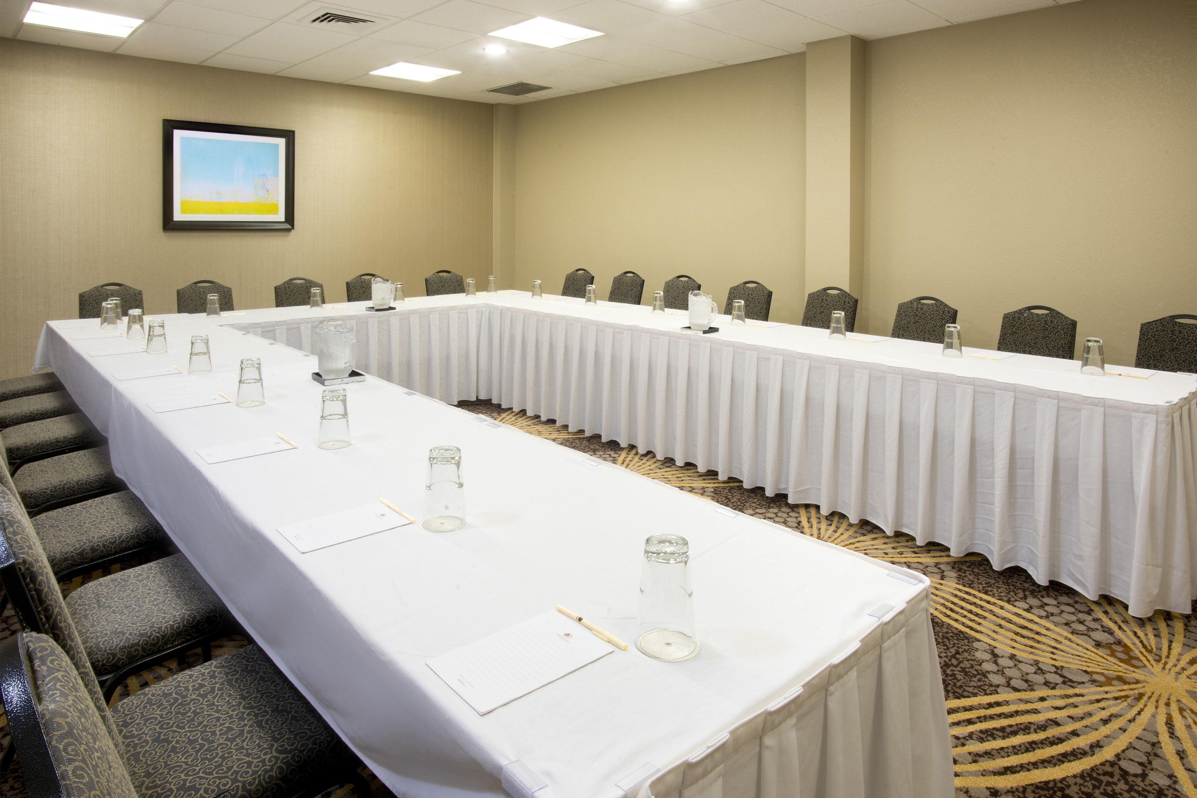 Une salle de conférence avec une longue table, des chaises et un sol recouvert de moquette.