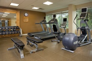 Ein Fitnessstudio mit Laufbändern, Crosstrainern und Kurzhanteln.