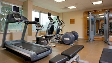 Un gimnasio con cintas de correr, elípticas y estaciones de pesas.