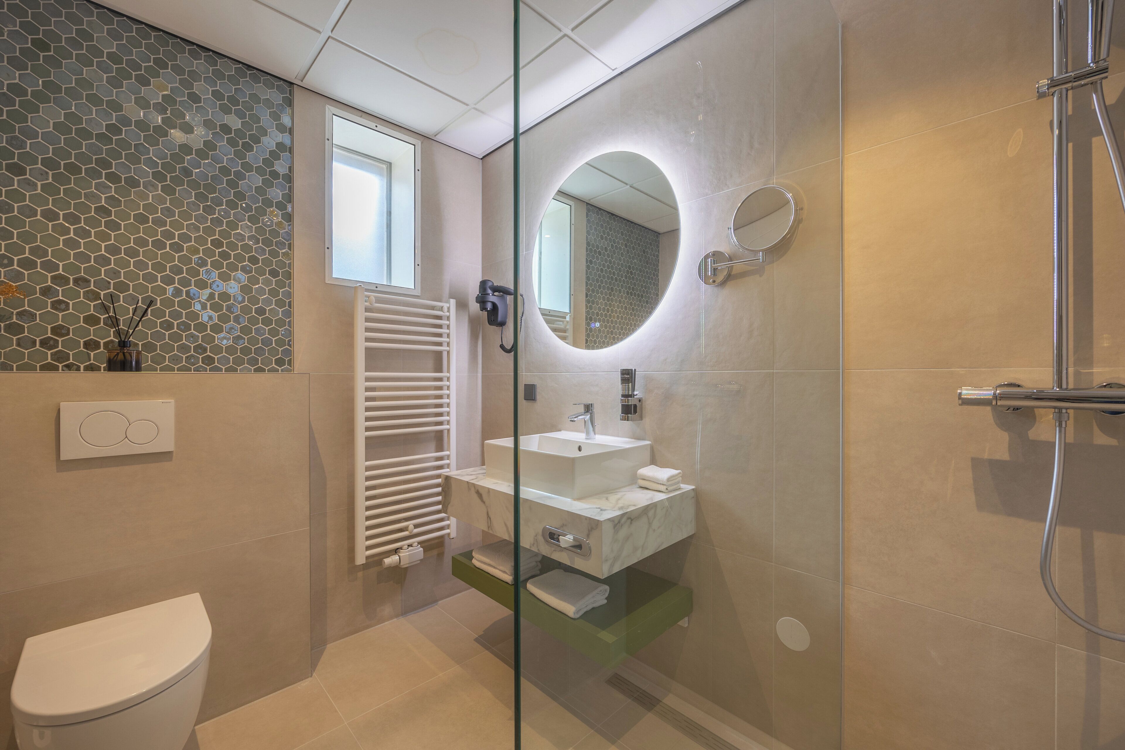 Un baño moderno con ducha envuelta en vidrio, un lavabo blanco y un inodoro.