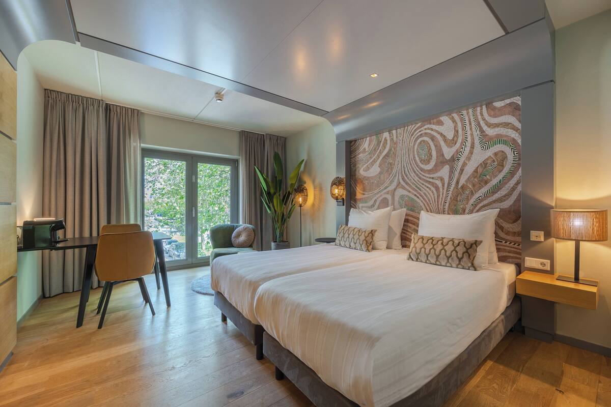 A modern bedroom with a large bed, a desk, and a chair.