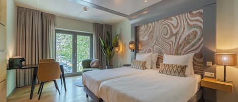 A modern hotel room with a large bed, a desk, and a view of the outdoors.