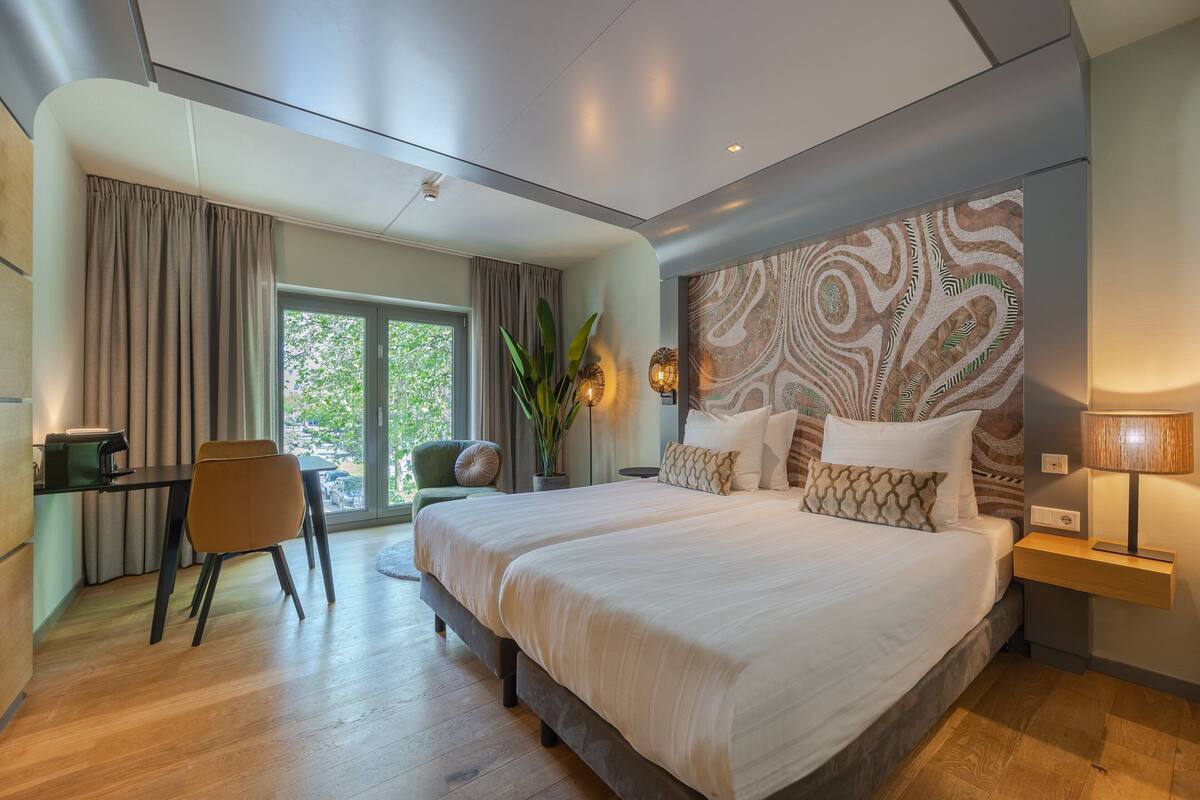 A modern bedroom with a large bed, a desk, and a chair.