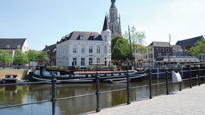 A historic building with a prominent tower, a canal with a boat, and a pedestrian walkway. - Leonardo Hotel Breda City Center (Breda)