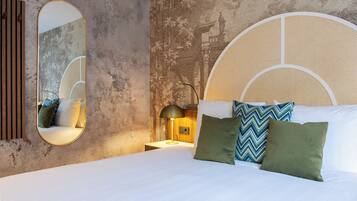 A bed with white linens, a round mirror, and a wall with a textured mural.