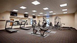 Une salle de sport équipée de tapis de course, de vélos elliptiques et de matériel de musculation.