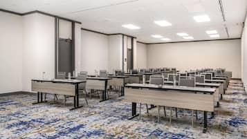 Une salle de conférence dotée de plusieurs tables et chaises, ainsi que de bouteilles d’eau et de stylos.