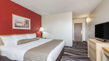 Une chambre d’hôtel avec un lit, une télévision, une lampe, un tableau au mur et un sol recouvert de moquette.