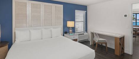 A bedroom with a large bed, a desk, and a chair.