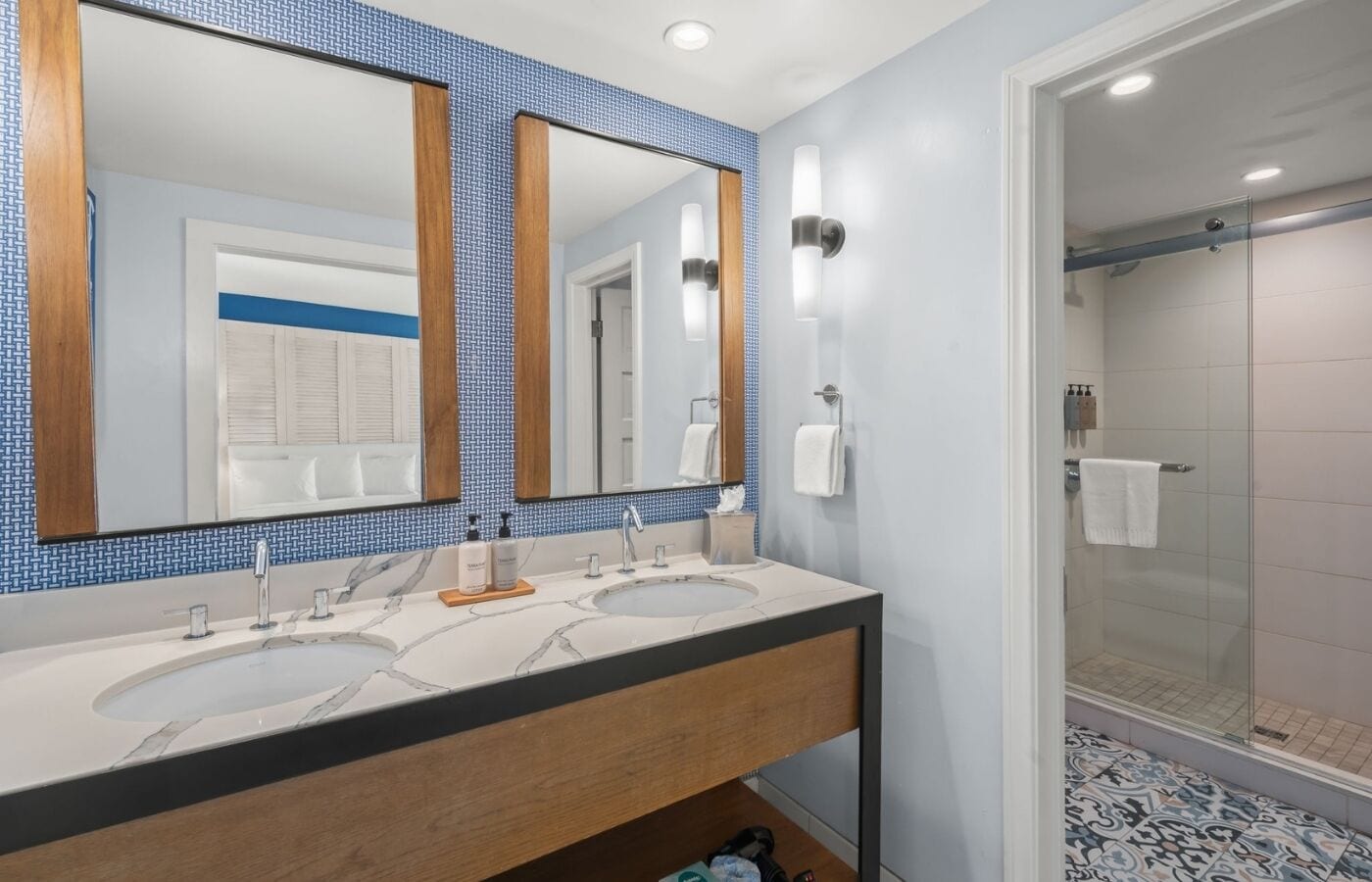 Een badkamer met twee wasbakken, een spiegel en een douche.