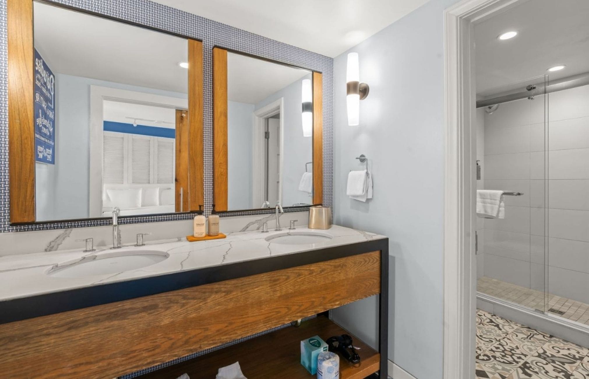 A bathroom with two sinks, a large mirror, and a shower area.