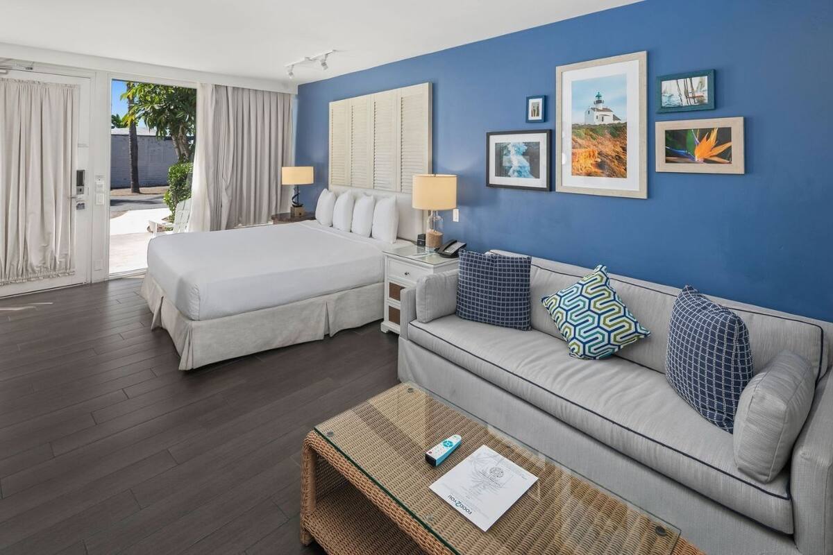 A hotel room with a bed, a sofa, a coffee table, and a wall with framed pictures.