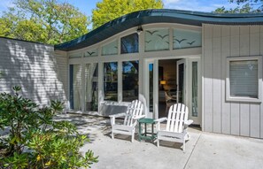 A two-story building with a covered patio area featuring two Adirondack chairs and a small table. - Paradise Point Resort & Spa (San Diego)