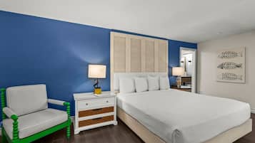Un dormitorio con cama, mesita de noche, una silla y una pared decorada con obras de arte.