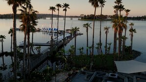 A waterfront hotel with a dock, palm trees, and a view of the water.