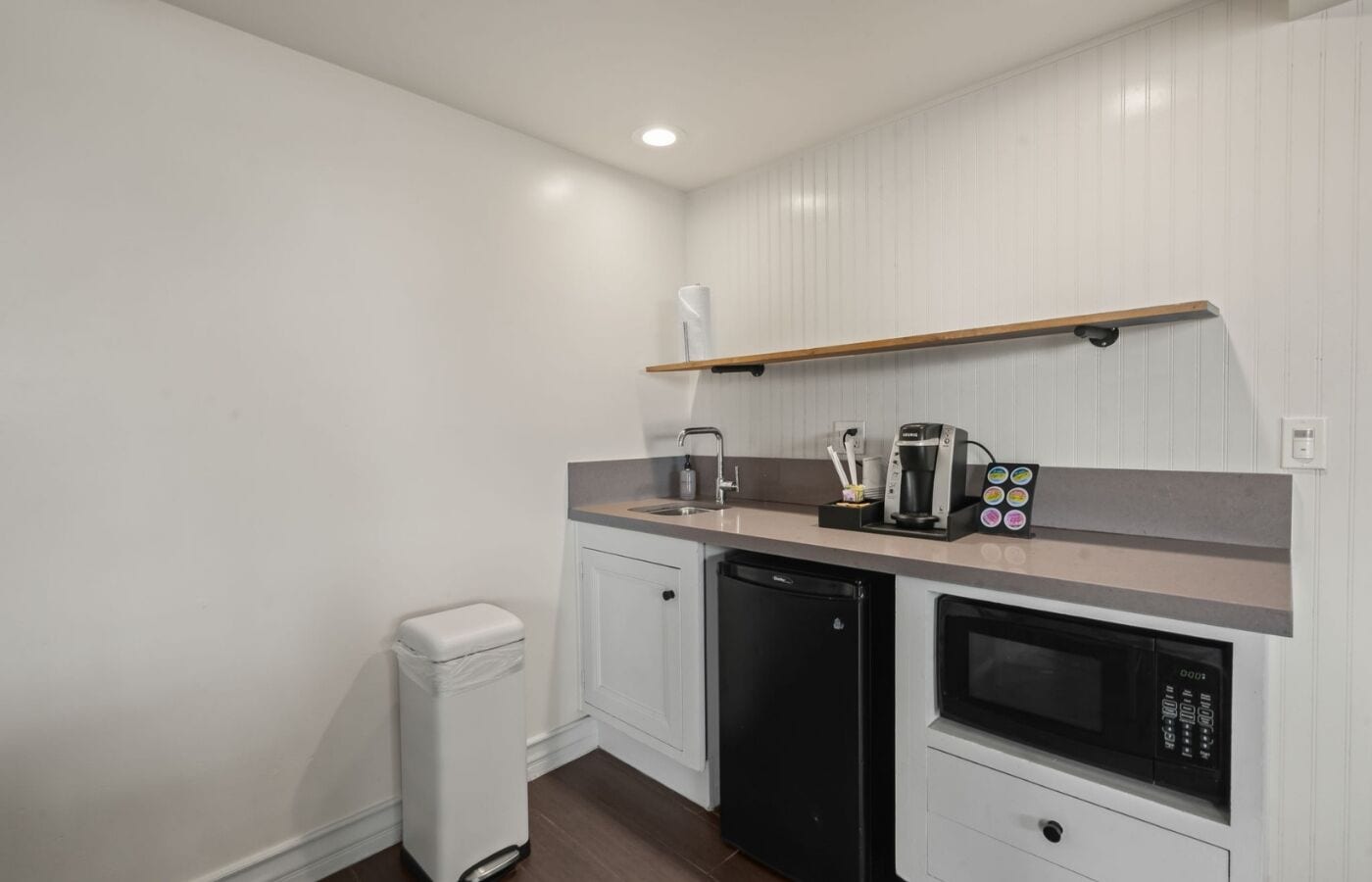 Una kitchenette compacta con lavavajillas integrado, cafetera y microondas.