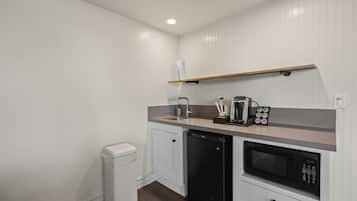 Una kitchenette compacta con lavavajillas integrado, cafetera y microondas.