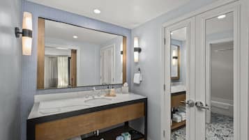 A modern bathroom with a large mirror, white sink, and wooden vanity.