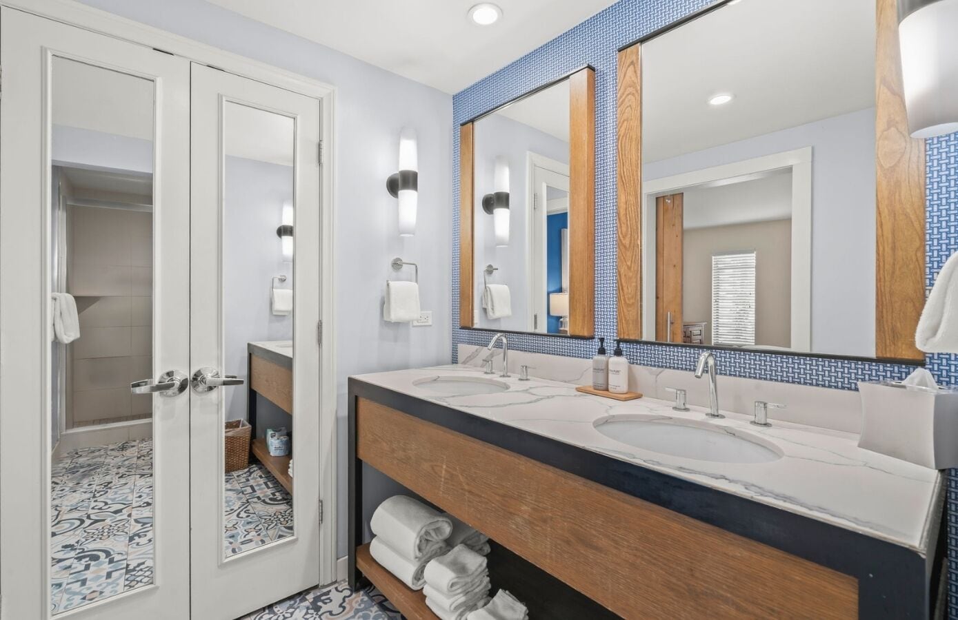 A modern bathroom with a double sink vanity, a large mirror, and a shower area.